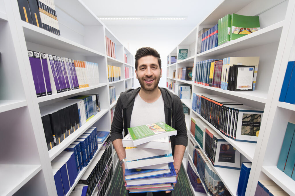 Student holding lot of books in school library - Christian Counselors of Mooresville