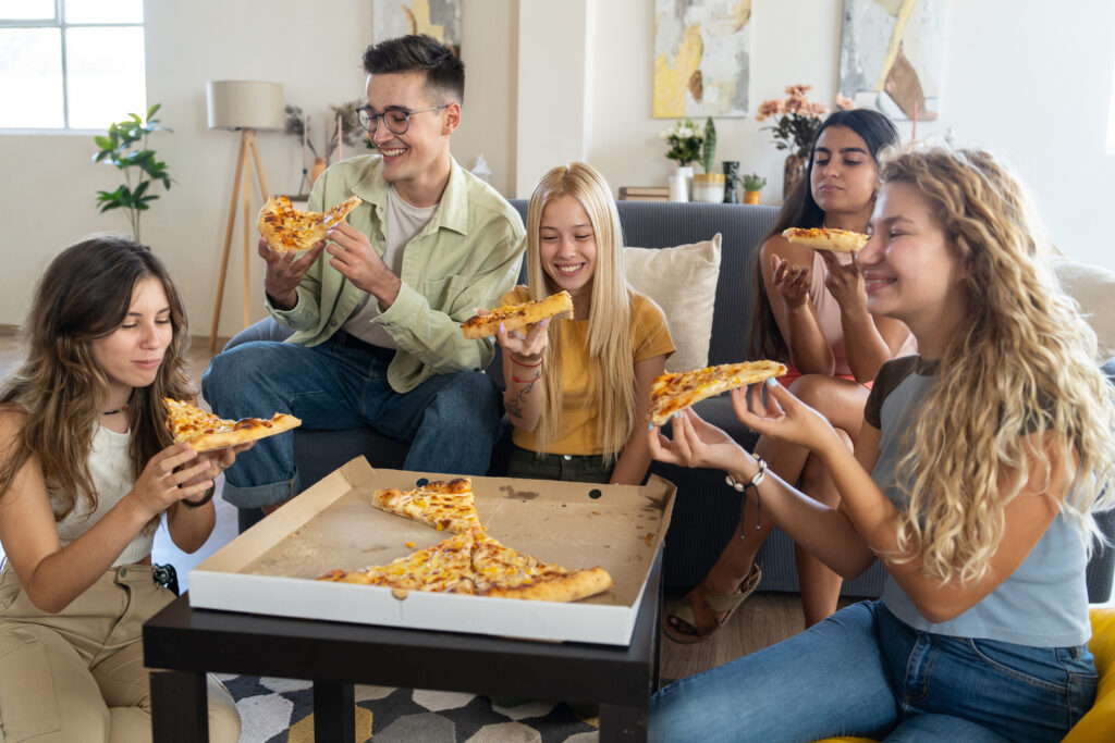 Group of People Eating Pizza on Couch - Christian Counselors of Mooresville Hanging out with friends can really improve your mental health and reduce stress.